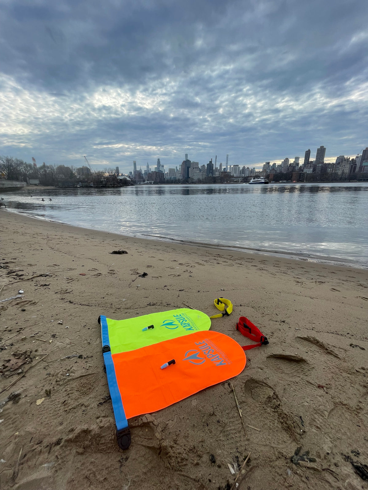 KAPSULE Aegis swim buoy neon orange and neon yellow high-visibility open water safety float on beach